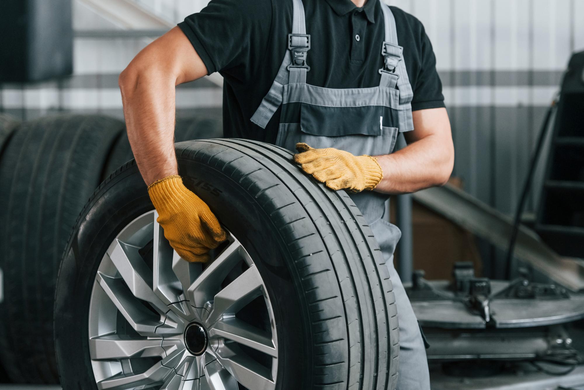 walking-holding-tyre-man-uniform-is-working-auto-service_146671-66343